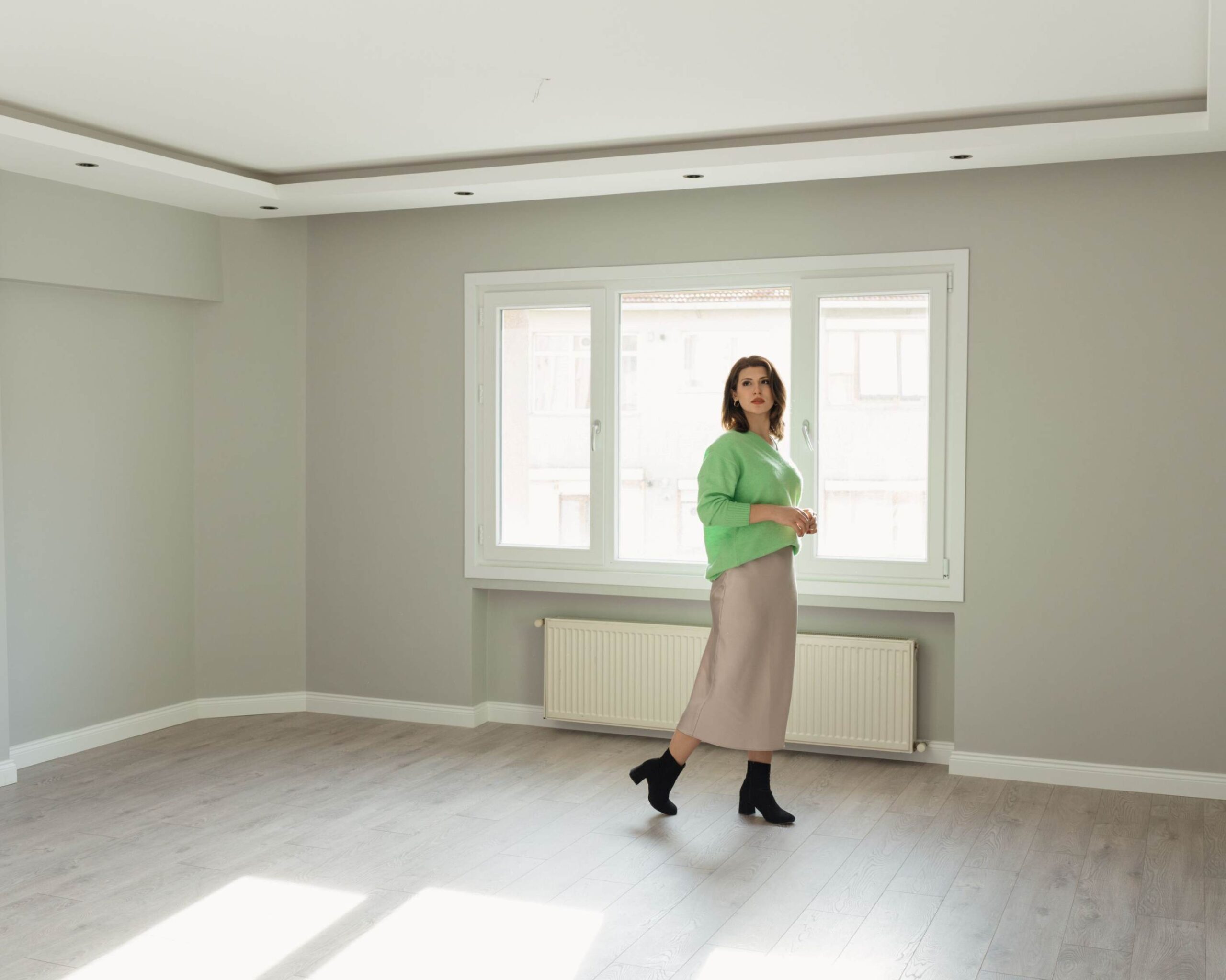 Woman at an open for inspection, walking through an empty room deciding if she wants to buy the property