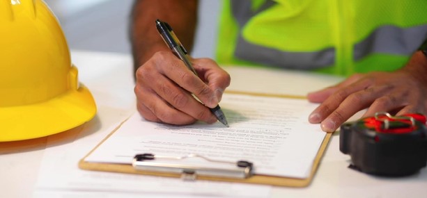 A construction hat on table with a builder filling out a dilapidation survey